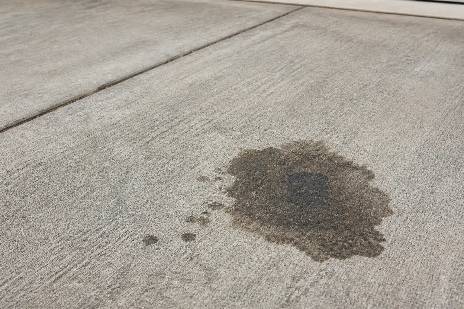 Illustrative close-up of an old oil stain embedded in a concrete driveway
